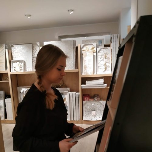 Ania uklada gazety kolorowe na regalach w sklepie